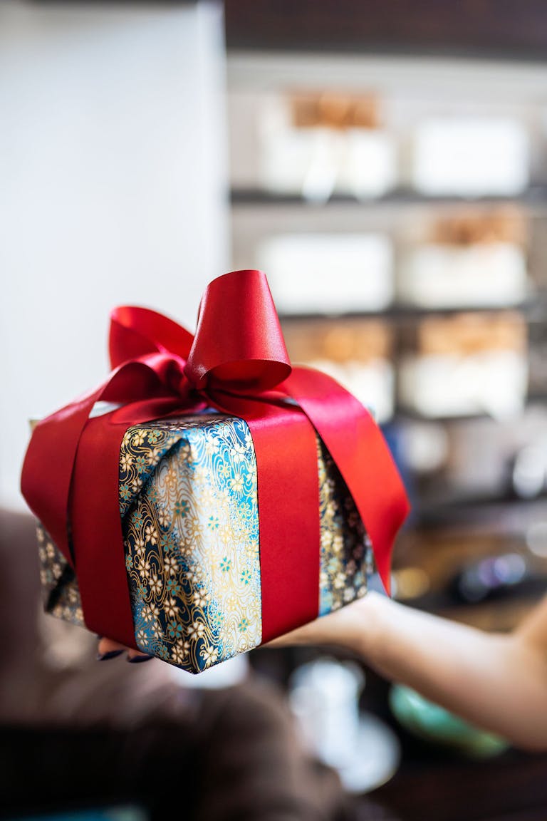 Close-up of a beautifully wrapped gift box with a vibrant red ribbon, perfect for celebrations.